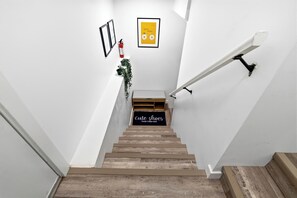 Eine Treppe mit Holzoptik, eine schwarze Matte mit weißer Schrift und ein gerahmtes Bild an der Wand.
