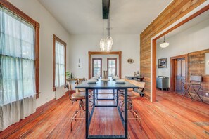 Uma sala de jantar com uma mesa comprida, cadeiras e um lustre.