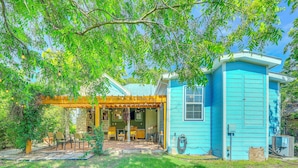 A small blue house with a covered patio area and a stone fireplace. - Walk to the Alamodome! Quirky Gem w/ Private Patio (San Antonio)