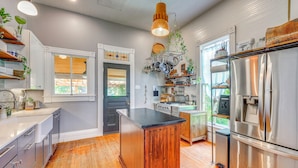 A kitchen with wooden flooring, stainless steel appliances, and a central island. - Walk to the Alamodome! Quirky Gem w/ Private Patio (San Antonio)