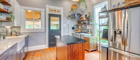 A kitchen with wooden flooring, stainless steel appliances, and a central island.