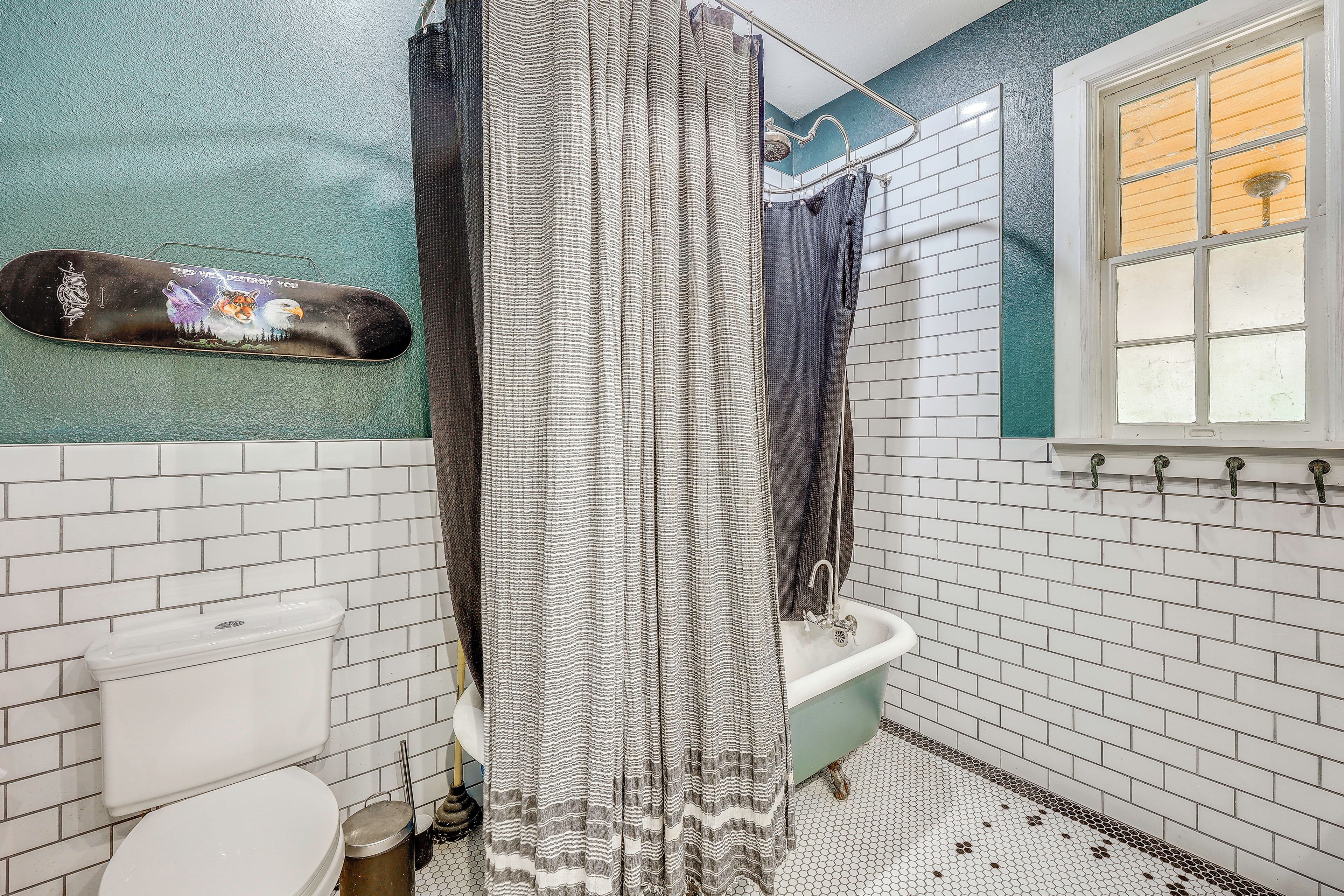 A bathroom with white subway tiles, a shower curtain, a toilet, and a bathtub.