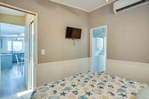 Ein Schlafzimmer mit einem Bett, einem an der Wand befestigten Fernseher und einer Tür zu einem Badezimmer.