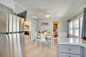 Eine moderne Küche mit einem Edelstahlkühlschrank, weißen Schränken und einem Essbereich mit Tisch und Stühlen.