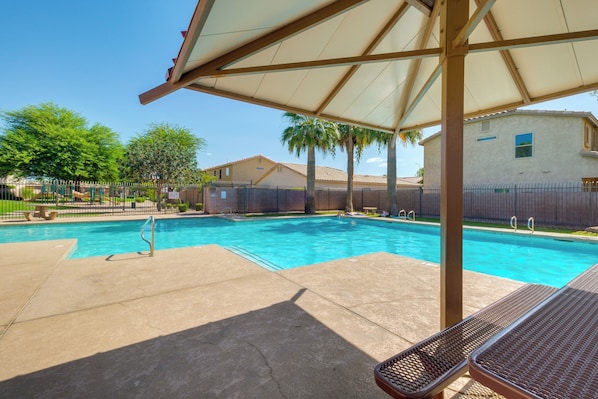 A swimming pool with a covered area and lounge chairs.