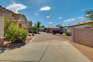 A residential street with houses, a driveway, and a parked SUV.
