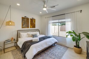 A bedroom with a bed, a ceiling fan, a window with curtains, a wall-mounted artwork, and a potted plant. - Relax Poolside! Retreat 2 Mi to Santan Mtn Casino (Chandler)