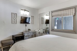 Ein Hotelzimmer mit Bett, Fernseher, Kommode, Spiegel und Fenster mit Blick.