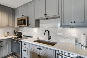 Eine moderne Küche mit grauen Schränken, Edelstahlgeräten und einer Marmor-Spritzschutzwand.