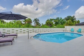 A swimming pool with a tiled deck, lounge chairs, and an umbrella. - 6 Mi to Siesta Beach! Extended Getaway w/ Pool (Sarasota)