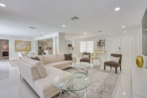 A modern living room with a beige sectional sofa, a glass coffee table, and two armchairs. - 6 Mi to Siesta Beach! Extended Getaway w/ Pool (Sarasota)