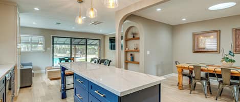 Una cocina moderna con una isla central, armarios empotrados e iluminación colgante.