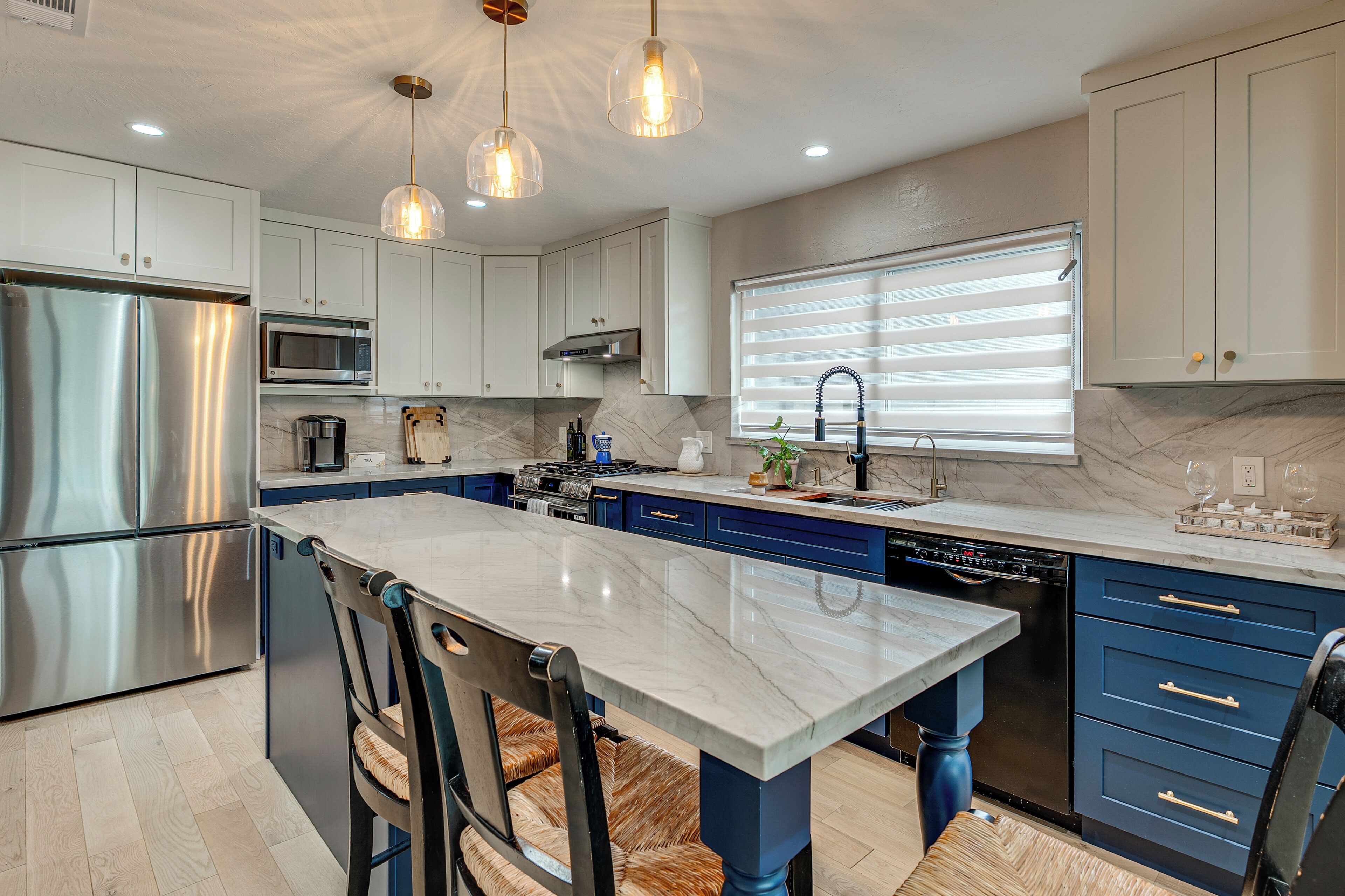 Una cocina moderna con electrodomésticos de acero inoxidable, encimera de mármol y muebles de color azul.