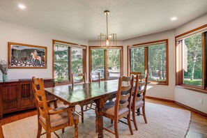 A dining room with a wooden table, chairs, a chandelier, large windows, and a painting on the wall. - Private Deck & Hot Tub! Family Sanctuary in Frisco (Frisco)