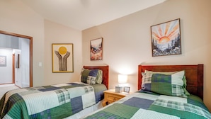 Ein Hotelzimmer mit zwei Betten, einem Nachttisch und drei an der Wand befestigten Kunstwerken.