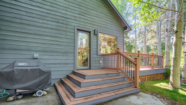 Ein Haus mit Veranda, Stufen zum Eingang und einem Grill vor der Tür.