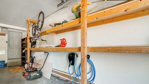 Eine Garage mit Fahrrad, Kettensäge und Elektrowerkzeug auf Regalen.