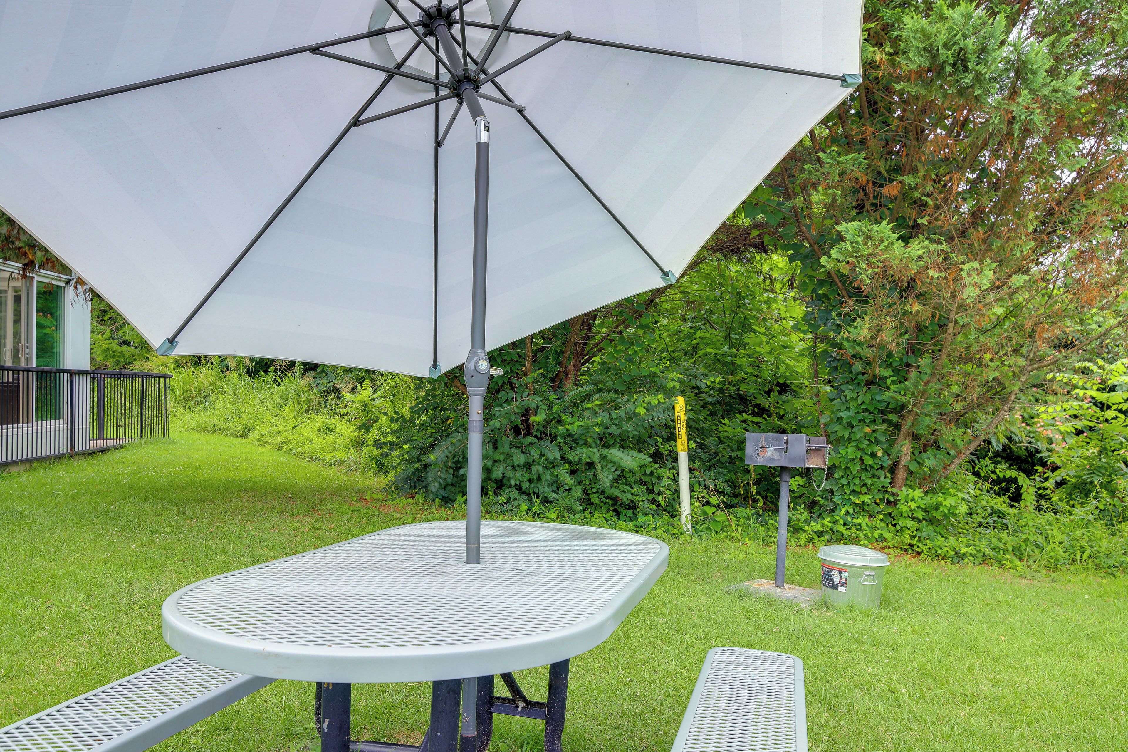 Ein Patio mit Tisch und Sonnenschirm, umgeben von viel Grün.