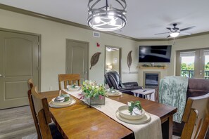 A dining area with a wooden table set for four, a television mounted on the wall, and a fireplace. - Mtn Views, Pool Access! Walkable Gem Near Parkway (Pigeon Forge)