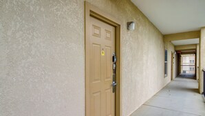 A hallway with a beige textured wall, a brown door with a peephole and a keyhole, and a metal intercom. - Mtn Views, Pool Access! Walkable Gem Near Parkway (Pigeon Forge)