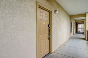 A hallway with a beige textured wall, a brown door with a peephole and a keyhole, and a metal intercom. - Mtn Views, Pool Access! Walkable Gem Near Parkway (Pigeon Forge)