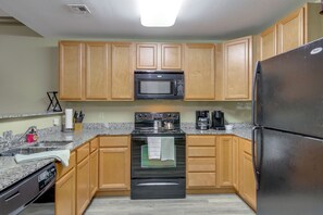 A kitchen with wooden cabinets, a stainless steel refrigerator, a microwave, a stove, and a dishwasher. - Mtn Views, Pool Access! Walkable Gem Near Parkway (Pigeon Forge)