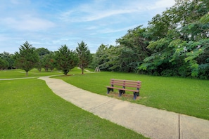 A park with a paved walkway, a bench, and trees. - Mtn Views, Pool Access! Walkable Gem Near Parkway (Pigeon Forge)