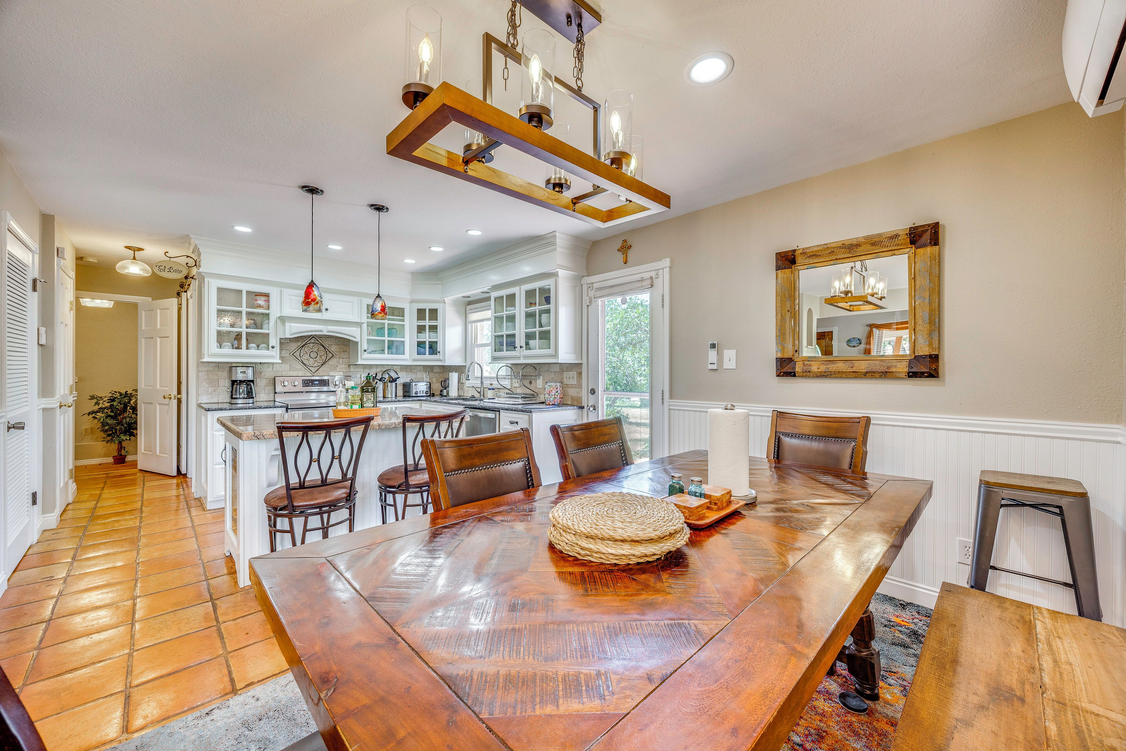 A spacious dining area with a large wooden table, multiple chairs, and a chandelier.