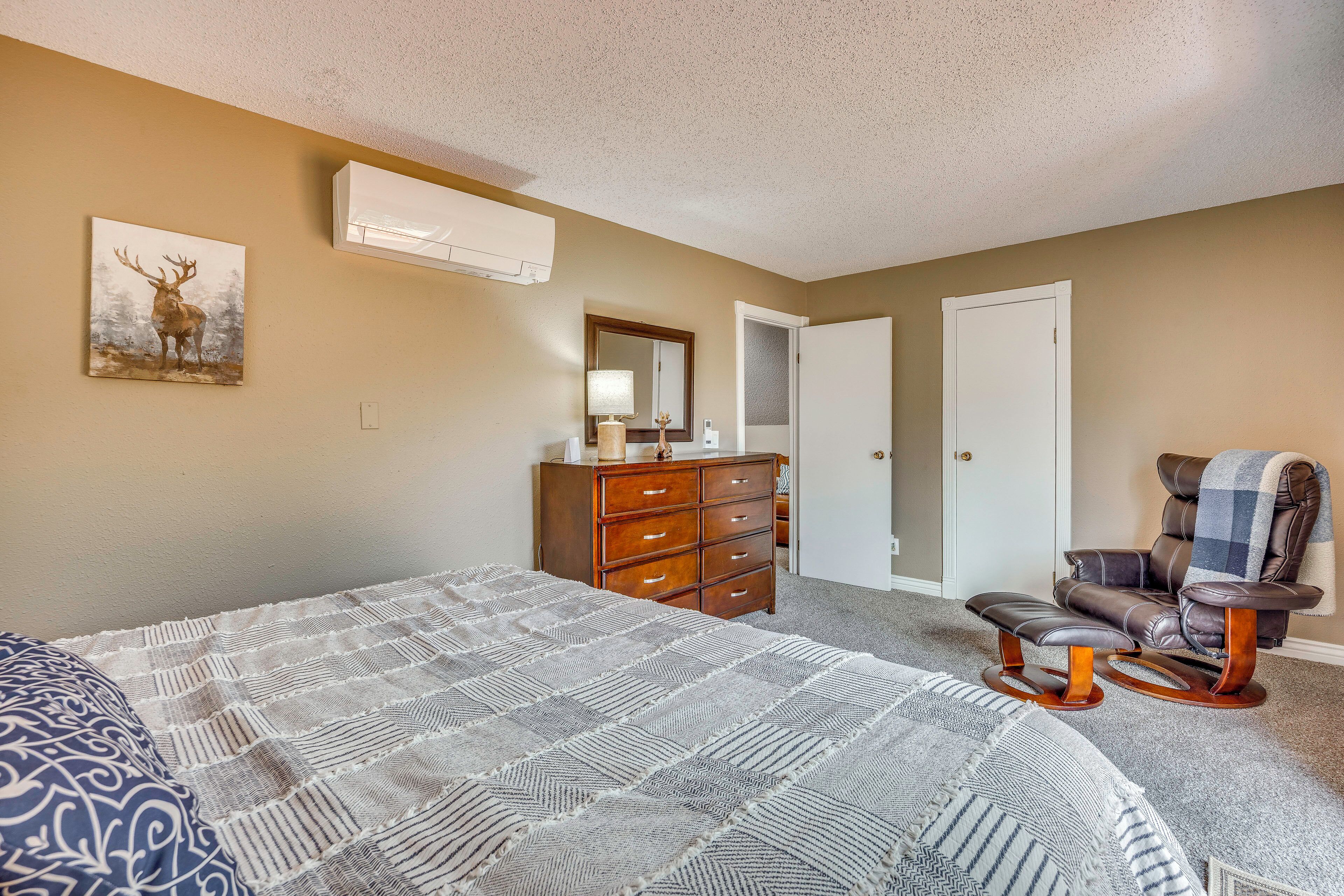 A bedroom with a large bed, a dresser, a chair, and a painting on the wall.