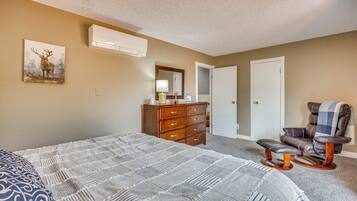A bedroom with a large bed, a dresser, a chair, and a painting on the wall.