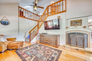 A living room with a wooden staircase, a fireplace, a television, and a patterned rug. - Hiking Days, Fireside Nights! Colorado Springs Gem (Colorado Springs)