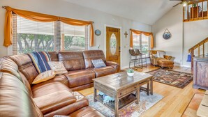 A spacious living room with a brown leather sectional sofa, a wooden coffee table, and a dining area with a chair and table. - Hiking Days, Fireside Nights! Colorado Springs Gem (Colorado Springs)