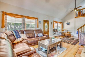 A spacious living room with a brown leather sectional sofa, a wooden coffee table, and a dining area with a chair and table. - Hiking Days, Fireside Nights! Colorado Springs Gem (Colorado Springs)