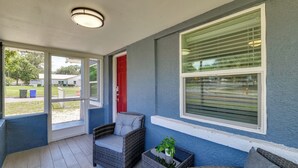 A covered porch with wicker furniture, a red door, and a window with blinds. - Modern Lakeland Retreat w/ Office I Fenced Yard (Lakeland)