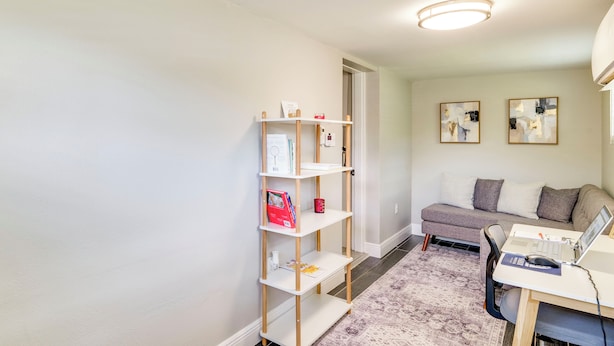 A room with a desk, a computer, a bookshelf, a sofa, and abstract wall art. - Modern Lakeland Retreat w/ Office I Fenced Yard (Lakeland)