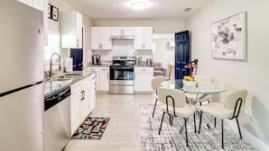 A modern kitchen with white cabinetry, a built-in oven, and a dining area with a glass table and chairs. - Modern Lakeland Retreat w/ Office I Fenced Yard (Lakeland)