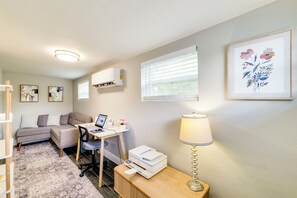 A modern living room with a sofa, desk, printer, lamp, and artwork on the walls. - Modern Lakeland Retreat w/ Office I Fenced Yard (Lakeland)