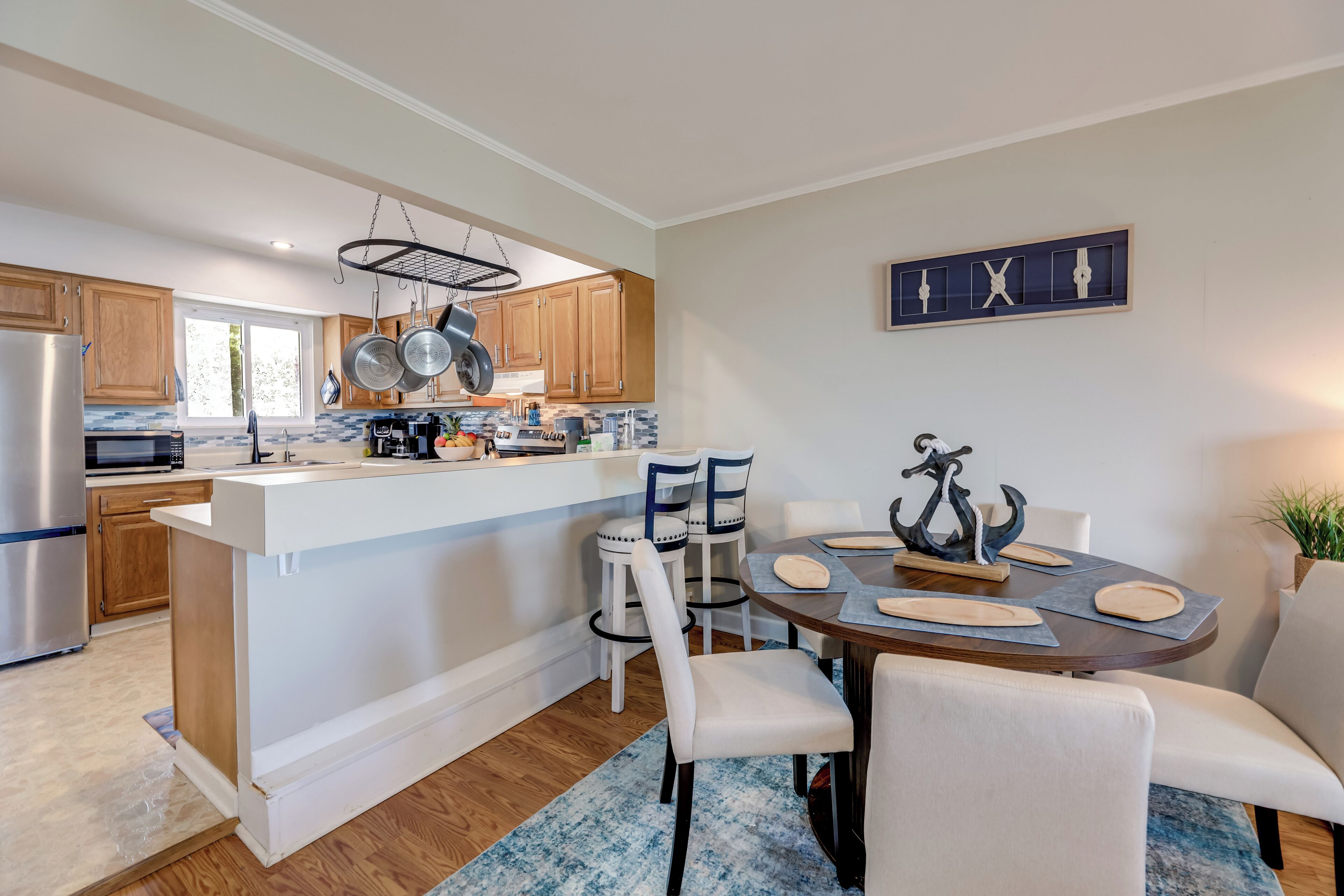 A modern kitchen with wooden cabinets, a stainless steel refrigerator, and a dining area with a round table and chairs.
