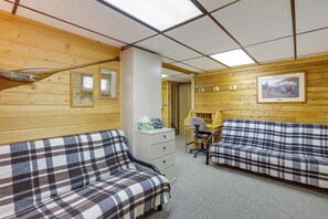 Una habitación con paredes de madera, dos sofás escoceses, un escritorio y una silla.