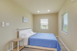 Ein Schlafzimmer mit einem Bett, Nachttisch, Fenster und einem Kunstwerk an der Wand.