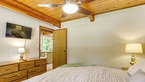 A bedroom with a bed, wooden dresser, bedside lamps, a ceiling fan, and a television on the wall. - Golf Getaway w/ Fairway Views Near Table Rock Lake (Eureka Springs)