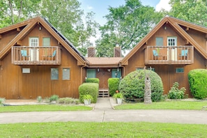 A wooden cabin with two balconies, a front porch, and a well-maintained garden. - Golf Getaway w/ Fairway Views Near Table Rock Lake (Eureka Springs)