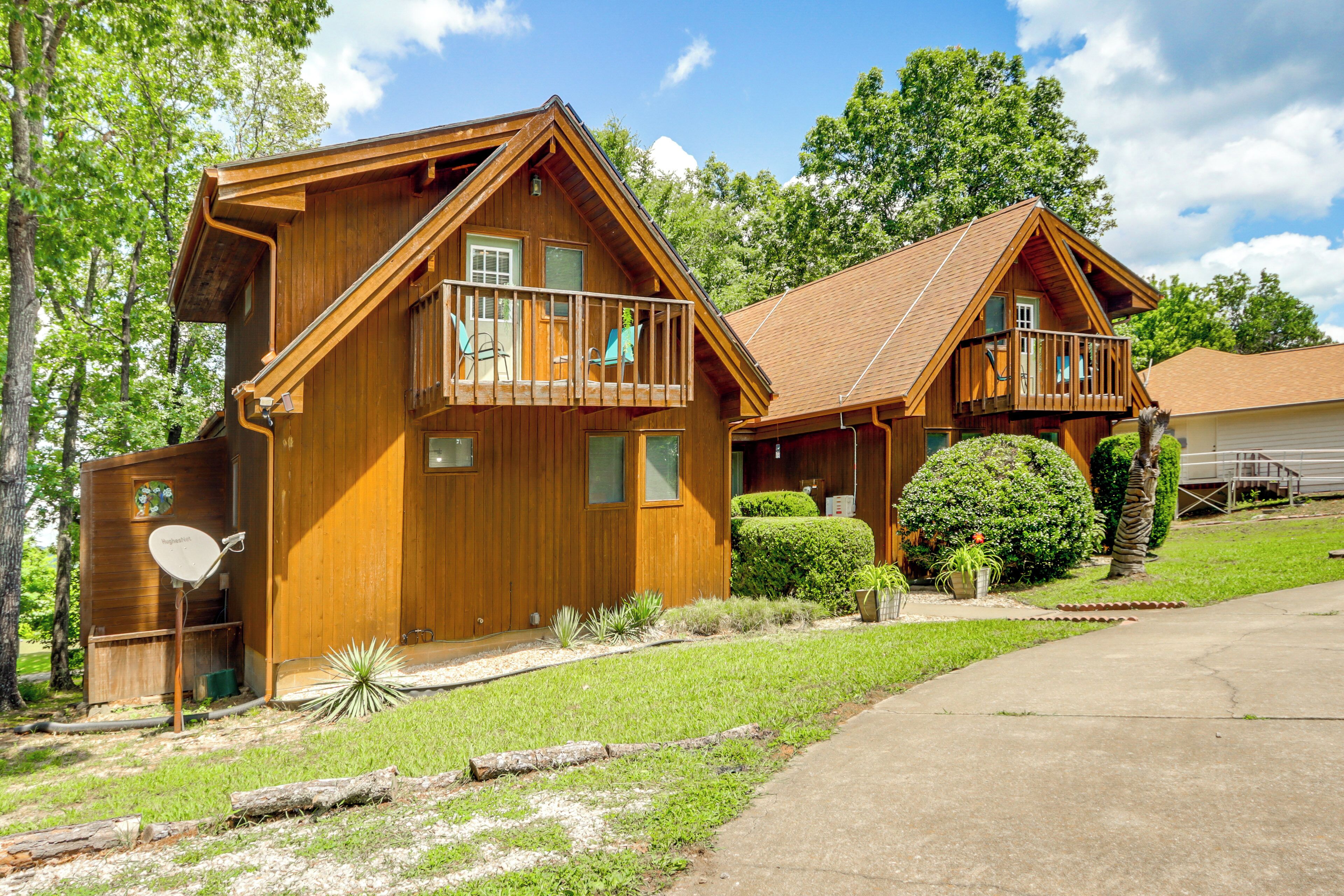 A wooden cabin with a balcony, a satellite dish, and a well-maintained lawn.
