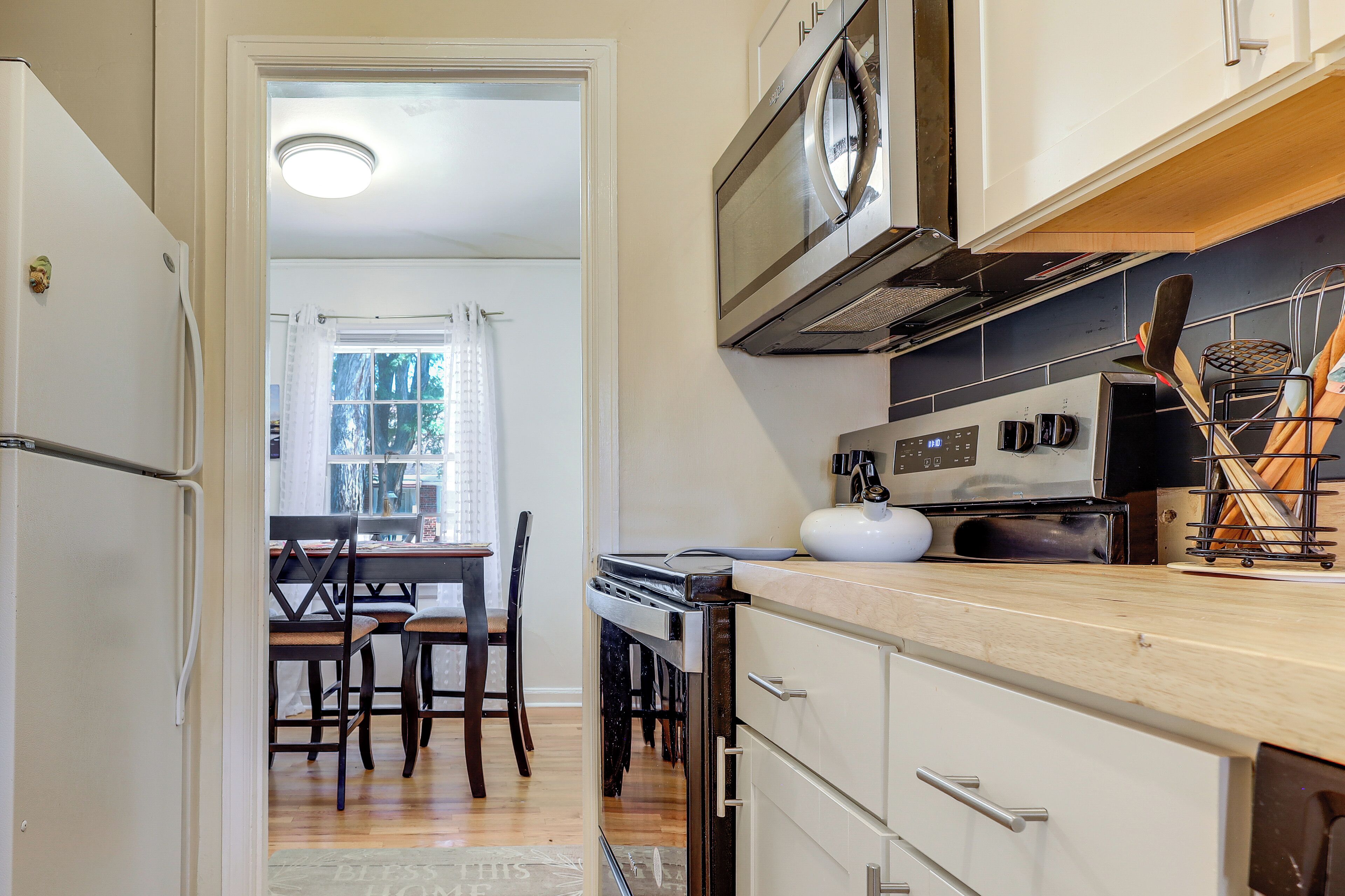 A kitchen with a refrigerator, oven, microwave, and a dining area with chairs and a table.