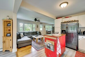 A modern kitchen with a built-in island, a refrigerator, and a dining area with a sofa and table. - Welcome to Buck's Hideout in Bridgton Maine! (Bridgton)