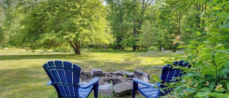 A grassy area with two blue chairs and a fire pit.