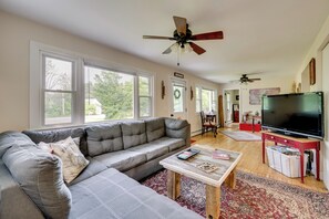 A living room with a sectional sofa, a coffee table, a TV, and a ceiling fan. - Welcome to Buck's Hideout in Bridgton Maine! (Bridgton)
