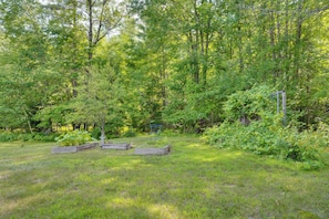 A natural outdoor setting with a wooden structure, possibly a deck or platform, surrounded by dense greenery and trees. - Welcome to Buck's Hideout in Bridgton Maine! (Bridgton)