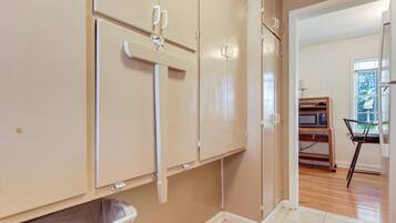 A room with beige walls, a trash bin, and a microwave on a shelf.