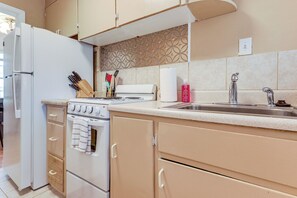 Una cocina con refrigerador, estufa, lavaplatos y gabinetes de madera.